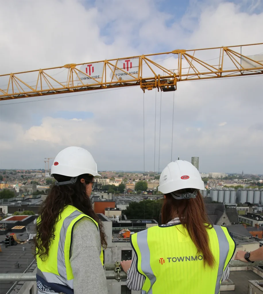 Two women looking over city from elevated rooftop