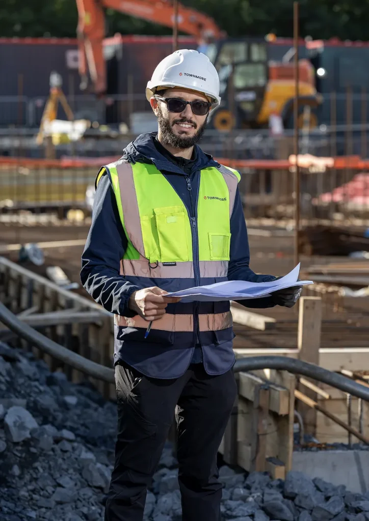 Man wearing construction gear on job site holding paper
