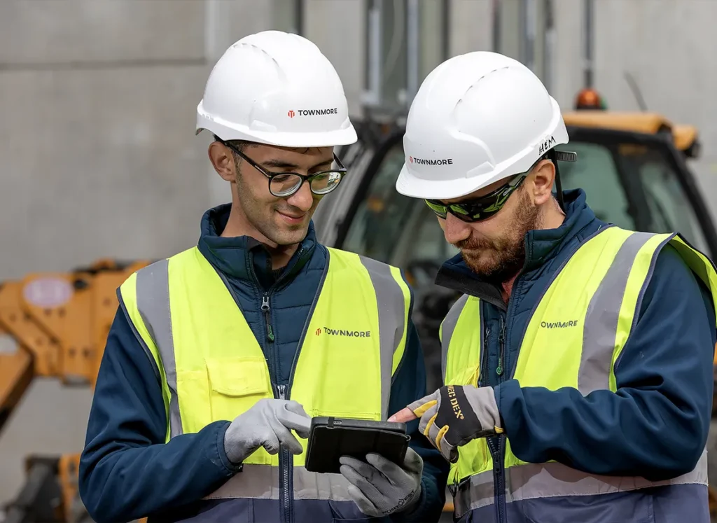 Men in construction looking at information on device