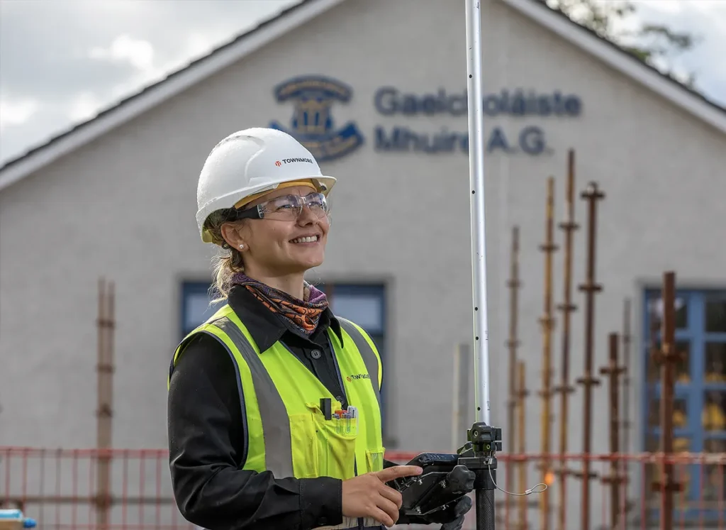 Woman in high vis and protectie helmet standing in front of scaffolding